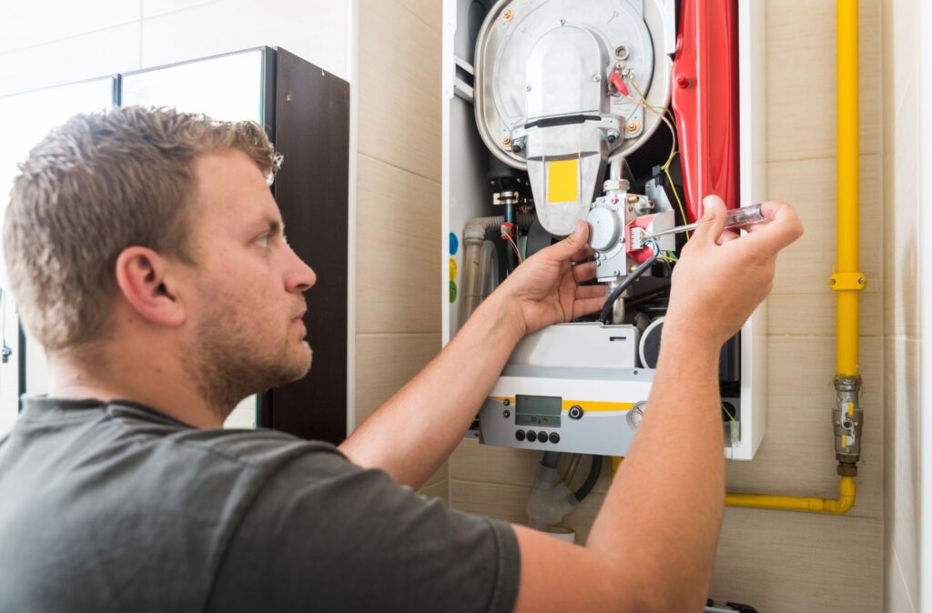 A technician repairs a gas boiler, focused on ensuring safe and efficient operation in a residential setting.